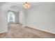 Open-concept living room featuring neutral carpeting, arched doorway, and natural light from the large window at 434 Antebellum Ln, Mount Pleasant, SC 29464