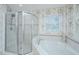 Bathroom features a shower, corner tub, white tile and floral wallpaper at 5847 Back Bay Dr, Isle of Palms, SC 29451