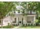 Charming two-story home with a large front porch and manicured lawn, framed by mature trees at 7053 Schooner St, Daniel Island, SC 29492