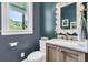 Elegant powder room featuring a marble countertop, wood cabinetry, and a decorative mirror at 7878 Gull Bay Dr, Awendaw, SC 29429