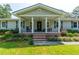 Welcoming front porch with classic columns, brick steps, and cozy seating amidst colorful landscaping at 806 Appii Rd, Moncks Corner, SC 29461