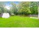 A fully fenced backyard with lush green grass, mature trees, and a storage shed at 100 Cheshire Dr, Goose Creek, SC 29445