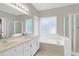 Bright bathroom featuring double sinks, soaking tub, and walk-in shower, creating a luxurious experience at 100 Cheshire Dr, Goose Creek, SC 29445