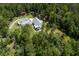 An aerial view reveals a beautiful white farmhouse-style home with lush greenery, and a long driveway at 105 Bobcat Ln, Ravenel, SC 29470