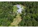 An aerial view shows a white farmhouse-style home nestled amongst lush greenery and a long winding driveway at 105 Bobcat Ln, Ravenel, SC 29470