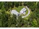 Aerial view showcasing a beautiful white farmhouse-style home nestled amongst lush greenery, and a circular driveway at 105 Bobcat Ln, Ravenel, SC 29470