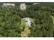 An aerial view shows a white farmhouse-style home amongst lush greenery and near a developing residential community at 105 Bobcat Ln, Ravenel, SC 29470