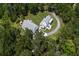 Areal view showcases a white farmhouse-style home nestled amongst lush greenery, and features a long winding driveway at 105 Bobcat Ln, Ravenel, SC 29470