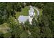 An aerial shot reveals a beautiful white farmhouse-style home with lush greenery, and a long driveway at 105 Bobcat Ln, Ravenel, SC 29470