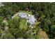 Aerial view showcasing a beautiful white farmhouse-style home nestled amongst lush greenery, and a circular driveway at 105 Bobcat Ln, Ravenel, SC 29470