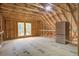 Unfinished attic with exposed beams, plywood flooring, two windows, and a refrigerator at 105 Bobcat Ln, Ravenel, SC 29470