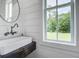 Bright bathroom featuring shiplap walls, a modern sink with a dark wood vanity, and a view to the green outdoors at 105 Bobcat Ln, Ravenel, SC 29470
