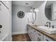 Well-lit bathroom featuring dual sinks, a large clock and vanity, and a tiled shower at 105 Bobcat Ln, Ravenel, SC 29470