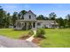 Stunning white farmhouse with a charming front porch and lush, well-maintained landscaping at 105 Bobcat Ln, Ravenel, SC 29470