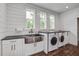 Modern laundry room with white cabinets, a stainless sink, dark countertop and side-by-side washer and dryer units at 105 Bobcat Ln, Ravenel, SC 29470