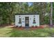 White, well maintained shed with double doors in a grassy backyard surrounded by trees at 105 Bobcat Ln, Ravenel, SC 29470