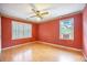 Red bedroom with hardwood floors, ceiling fan, and a window with shutters and air conditioner at 117 Myer Ln, Goose Creek, SC 29445