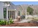 A patio features outdoor dining with a grill near a white farmhouse-style home with a screened-in porch at 1174 Hitchfield Ln, Awendaw, SC 29429