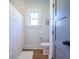Well-lit bathroom with a toilet and shower with a white curtain, next to a door at 1174 Hitchfield Ln, Awendaw, SC 29429