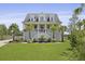 Charming two-story beach home with a lush green lawn, a picturesque porch, and beautiful palm trees at 1216 Rivers Reach Dr, Charleston, SC 29492