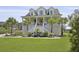 Charming two-story yellow home with a porch, tropical plants, and a well-manicured lawn at 1216 Rivers Reach Dr, Charleston, SC 29492