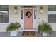 Welcoming pink front door with a wreath, flanked by potted plants and stylish wall lanterns at 1216 Rivers Reach Dr, Charleston, SC 29492