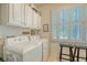 Bright laundry room with white cabinets, washer, dryer, and window with plantation shutters at 1308 Divot Ct, Mount Pleasant, SC 29466