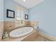 A blue bathroom showcases a tiled soaking tub beneath a shuttered window, creating a relaxing atmosphere at 1597 Rivertowne Country Club Dr, Mount Pleasant, SC 29466
