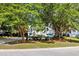 A white home with a garage and small porch is framed by mature trees and manicured landscaping at 1635 Bull Creek Ln, Charleston, SC 29414