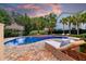 Beautiful pool area with a rock wall, waterfall feature, lounge chairs, and meticulous landscaping at dusk at 1635 Bull Creek Ln, Charleston, SC 29414