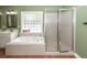 Bright bathroom featuring a soaking tub, glass block window, and a glass-enclosed shower at 1648 Secessionville Rd, Charleston, SC 29412