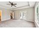 Spacious carpeted main bedroom featuring tray ceiling, fan, doors to patio, stairs to another floor, and a window at 206 Almond Ct, Summerville, SC 29483