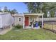 A charming shed with a red door and small windows, surrounded by lush greenery and garden supplies at 212 Columbia Dr, Ladson, SC 29456