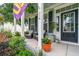 Inviting front porch with comfortable seating, ferns, beautiful green landscaping, and flag at 216 Foxbank Plantation Blvd, Moncks Corner, SC 29461