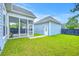 Well-maintained backyard with green grass, screened porch, and detached blue garage under a sunny, partly cloudy sky at 310 Marchman St, Summerville, SC 29486