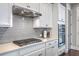Close-up of a gas cooktop with stainless vent hood and gray subway tile backsplash at 310 Marchman St, Summerville, SC 29486