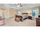 Large primary bedroom with tray ceilings, multiple windows with curtains, and stylish dark wood furniture at 407 Glenmore Dr, Moncks Corner, SC 29461