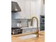 Close up of a gold kitchen faucet, stainless appliances, and white herringbone backsplash at 4073 Blackmoor St, Mount Pleasant, SC 29466