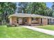 Charming brick home featuring a well-manicured lawn, green door, and a convenient covered parking area at 5172 Sterrett St, North Charleston, SC 29405