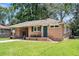 Charming brick home featuring a well-manicured lawn, green door, and a convenient covered parking area at 5172 Sterrett St, North Charleston, SC 29405
