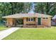 Charming brick home featuring a well-manicured lawn, green door, and a convenient covered parking area at 5172 Sterrett St, North Charleston, SC 29405