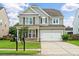 Two-story home showcasing a well-manicured lawn, gray siding, and a two-car garage under a partly cloudy sky at 535 Crossland Dr, Moncks Corner, SC 29461
