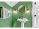 Modern powder room with green walls, decorative mirror, and wall sconces at 5725 Caviar Ct, Johns Island, SC 29455
