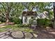 Quaint white outbuilding with a green door and shingle roof, complemented by lush greenery and a stone pathway at 708 Pitt St, Mount Pleasant, SC 29464