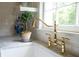 Close-up of a kitchen sink with brass fixtures and a window view at 708 Pitt St, Mount Pleasant, SC 29464