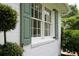 A window with green shutters and white brick. A decorative bush sits to the left at 708 Pitt St, Mount Pleasant, SC 29464