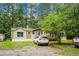 Charming single-story home featuring a front yard with mature trees offering shade and privacy, parked cars visible at 785 Coral Acres Dr, Moncks Corner, SC 29461