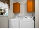 Bright laundry room with side-by-side white washer and dryer under wood cabinets at 785 Coral Acres Dr, Moncks Corner, SC 29461