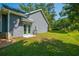 View of the backyard, showcasing a well-maintained lawn, wooded backdrop, and light blue siding with matching doors at 8453 Charleston Hwy, Walterboro, SC 29488