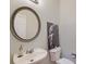 Powder room featuring a round mirror, white sink and toilet with modern fixtures at 9682 Pebble Creek Blvd, Summerville, SC 29485